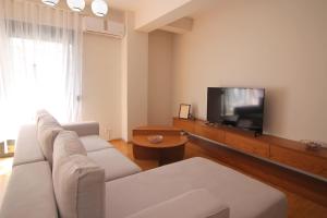 a living room with a white couch and a flat screen tv at Motra Apartment in Metogjashta