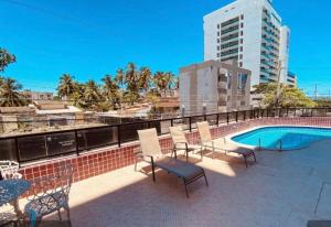 a patio with chairs and a swimming pool on a building at Ap studio a 50m da praia in Maceió +4 photos