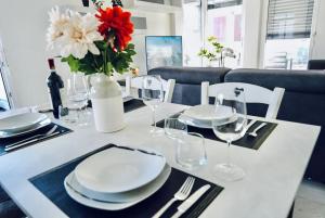 une table avec des assiettes et des verres et un vase avec des fleurs dans l'établissement Lakeside Attic, à Lugano