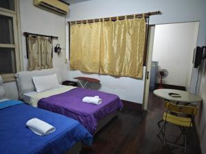 a room with two beds and a table and a window at Gold house apartment in Vientiane