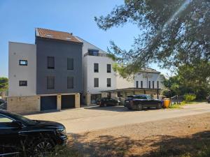 deux voitures garées sur un parking devant un immeuble dans l'établissement Apartman Marlera s privatnim bazenom, à Ližnjan