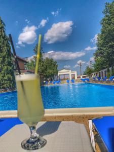 ein Getränk auf einem Tisch neben einem Pool in der Unterkunft Hotel President in Scorniceşti