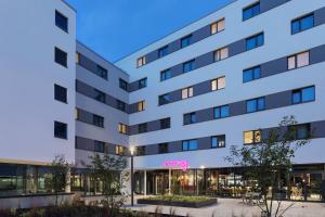 a white building with a pink sign on it at Moxy Hamburg Altona in Hamburg