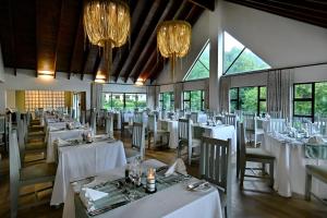 una sala da pranzo con tavoli e sedie bianchi e lampadari a braccio di Champagne Castle Hotel a Champagne Valley