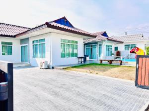 a white house with a patio in front of it at Victoria Poolvilla Pattaya by Chon in Nong Prue