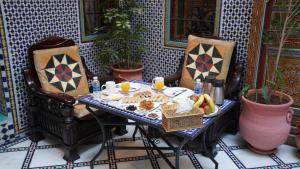 a table with food on it with two chairs at Riad Green House in Fès
