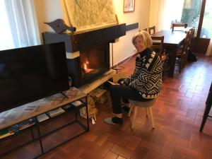 an older woman sitting in a chair in front of a fireplace at L'Onyx - Domaine de Nant Cruy in Sallanches