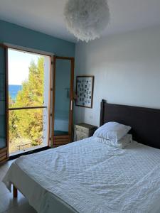 una camera da letto con un letto e una grande finestra di Maison à 50 m de la plage, 10 personnes, 5 chambres en corse du sud, a Coti-Chiavari