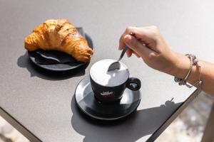 a person eating a cup of coffee and a croissant at Il Grottino Relais & Spa in Gualdo Cattaneo