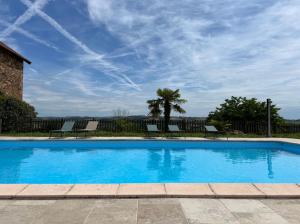 a swimming pool with chairs and a blue sky at Gîtes & Chambres d'hôtes Peyrecout in Laparrouquial