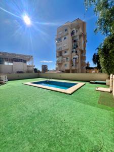 een grote tuin met een zwembad voor een gebouw bij Loft beach in Alicante