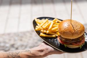 a person holding a plate with a hamburger and french fries at Il Grottino Relais & Spa in Gualdo Cattaneo