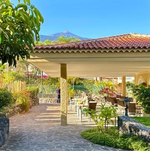 a pavilion with people sitting at tables in a garden at Apartamentos Tigaiga Suites in Puerto de la Cruz