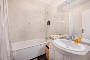a white bathroom with a sink and a bath tub at Appartement proche du Parc de la Tête d'Or - Garage Gratuit in Villeurbanne +9 photos