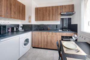 a kitchen with wooden cabinets and a table with a sink at Appartement proche du Parc de la Tête d'Or - Garage Gratuit in Villeurbanne