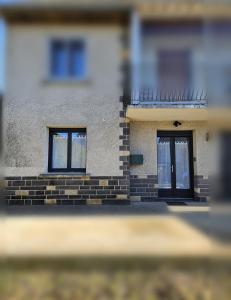 un edificio con due finestre e una porta di Appartement cosy proche du Mont-Dore a Laqueuille