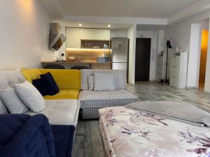 a living room with a yellow couch and a kitchen at Summer cosmopolis in Creţuleasca