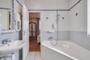 a bathroom with a bath tub and a sink at Hotel Lepante in Nice