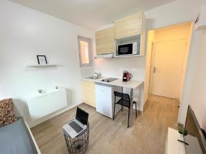 a small kitchen with a desk and a table with a laptop at cosy studio Nanterre- La defense in Nanterre
