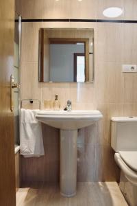 a bathroom with a sink and a mirror and a toilet at Casa India in Muros de Nalón