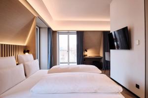 two beds in a hotel room with a tv at 4K - Rooftop-Pool und klimatisierte Zimmer in Wangen im Allgäu