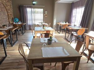 a restaurant with wooden tables and chairs and windows at Crayfish Creek Guest House in Richards Bay