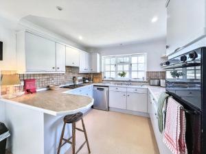 une cuisine avec des placards blancs et un grand îlot dans l'établissement Tranquil 2-Bed Nature Cottage with Free Parking, à Newick