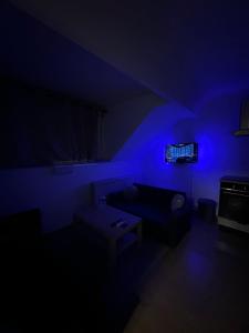 une pièce sombre avec un canapé et une lumière bleue dans l'établissement Elegance & Comfort Brand New Apartment near to Atomium, à Bruxelles