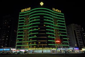 a tall building with green lights on it at night at Emirates Stars Hotel Apartments Dubai in Dubai