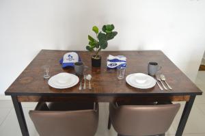 a wooden table with plates and utensils on it at Beautiful Salalah Beach Apartments - 3 By Beautiful Salalah Tours in Salalah