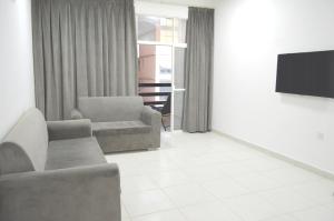 a living room with a couch and a flat screen tv at Beautiful Salalah Beach Apartments - 3 By Beautiful Salalah Tours in Salalah
