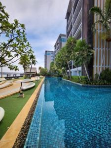 a swimming pool in a resort with palm trees and buildings at Metro luxe riverfront resort style condo in Ban Sai Ma