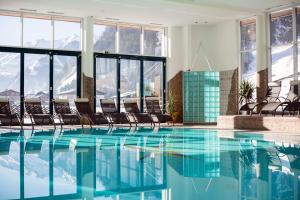a hotel swimming pool with chairs and mountains in the background at Rauriserhof 4 Sterne Superior in Rauris