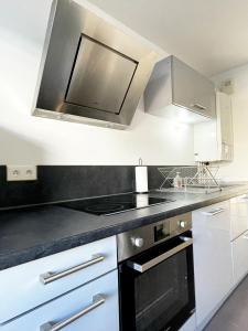 a kitchen with white cabinets and a black stove top oven at Dream Saint-Georges à proximité de Disneyland in Bussy-Saint-Georges +13 photos