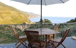 einen Tisch und Stühle auf einem Balkon mit Sonnenschirm in der Unterkunft Cottage con vista mozzafiato sul mare - Monterosso al mare in Monterosso al Mare