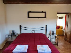 a bedroom with a red bed with two white towels at Casa del Contadino in Sansepolcro