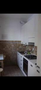una cucina con mobili bianchi e un forno a piano cottura di Casa in montagna a Badi a Suviana