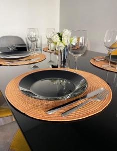 a table with a black plate and wine glasses at Dream Saint-Georges à proximité de Disneyland in Bussy-Saint-Georges