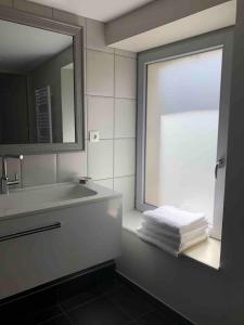 a bathroom with a sink and a window and towels at Maison de pêcheur à 1,5km de la mer in Blainville-sur-Mer