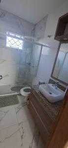 une salle de bain blanche avec un lavabo et des toilettes dans l'établissement Casa da Naná - Praia da Gamboa - Garopaba, à Garopaba