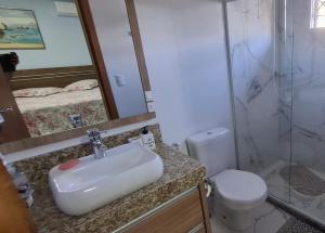 une salle de bain avec un lavabo, des toilettes et un miroir dans l'établissement Casa da Naná - Praia da Gamboa - Garopaba, à Garopaba 2 autres photos