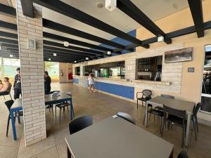 a cafeteria with tables and chairs and a kitchen at Apto Solar das Águas Olimpia SP in Olímpia