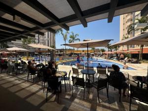 a group of people sitting at tables near a swimming pool at Apto Solar das Águas Olimpia SP in Olímpia