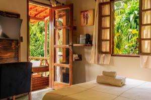 a room with a bed and a door with a window at Pousada Aquarela in Morro de São Paulo