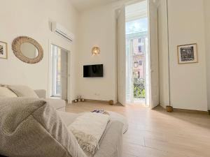 een witte woonkamer met een bank en een tv bij UniHome Napoli in Napels