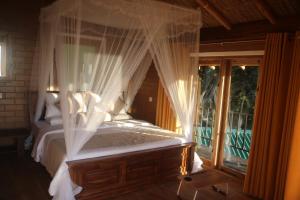 a bedroom with a canopy bed and a window at Jungle Cave in Ella