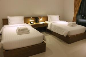 two beds in a hotel room with towels on them at Crystal Lamai Hotel in Lamai