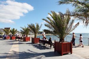 a group of people sitting on benches by the water at Le Royal Parc - Appartement au calme au coeur de Bénodet in Bénodet