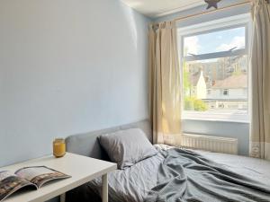 a bedroom with a bed and a table and a window at Cozy sunlit room in west London in Yiewsley