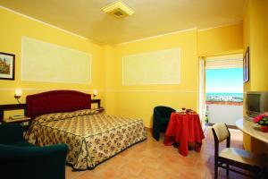 Schlafzimmer mit einem Bett, einem Tisch und einem TV in der Unterkunft Hotel Tarconte in Tarquinia
